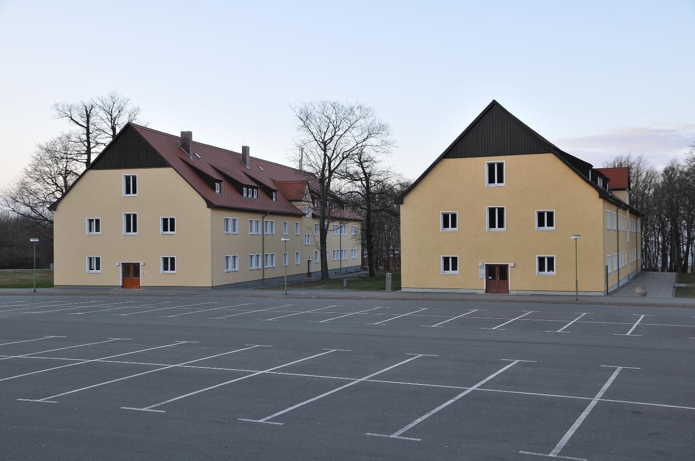 Die Internationale Begegnungsstätte der Gedenkstätte Buchenwald. Zwei ehemalige, inzwischen umgebaute SS-Kasernen, davor ein leerer Parkplatz
