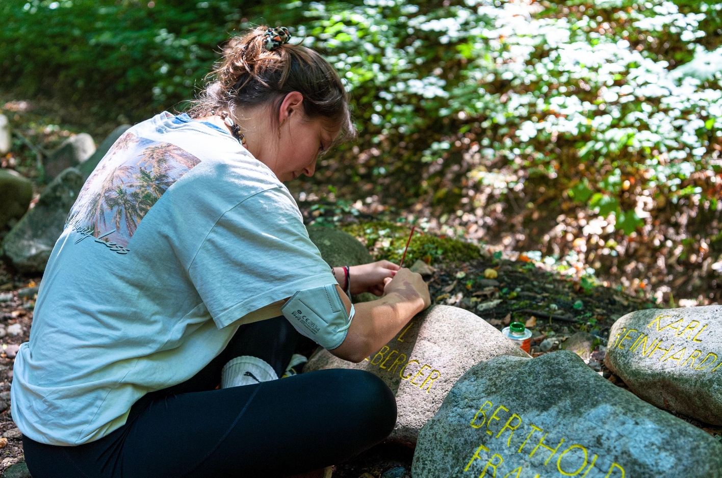 A participant of the Summerworkcamp paints memorial stones.