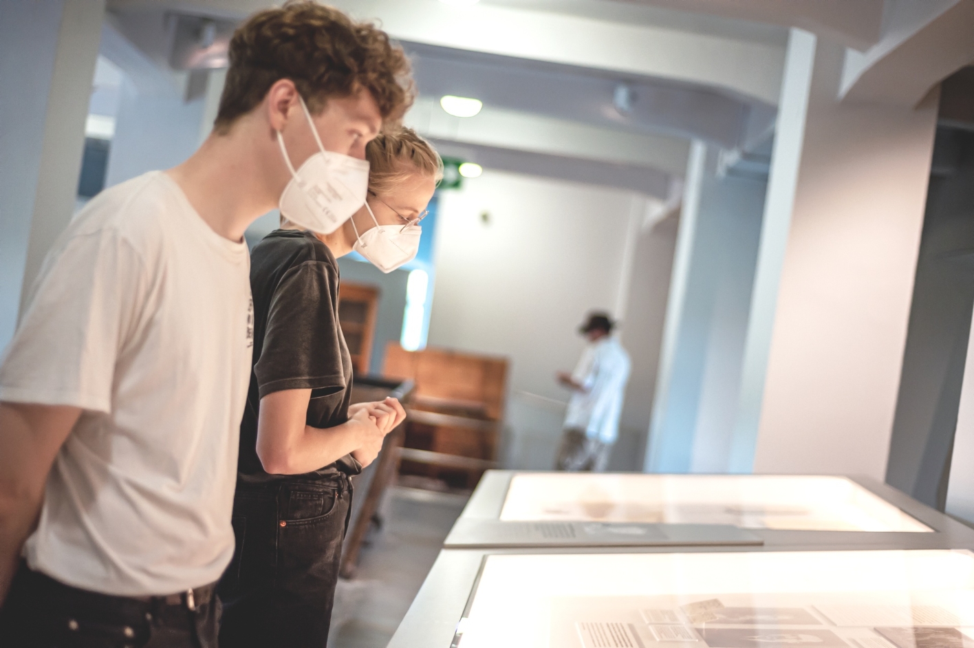 Two young visitors stand in front of a display cabinet in the exhibition in the former chamber building. 
