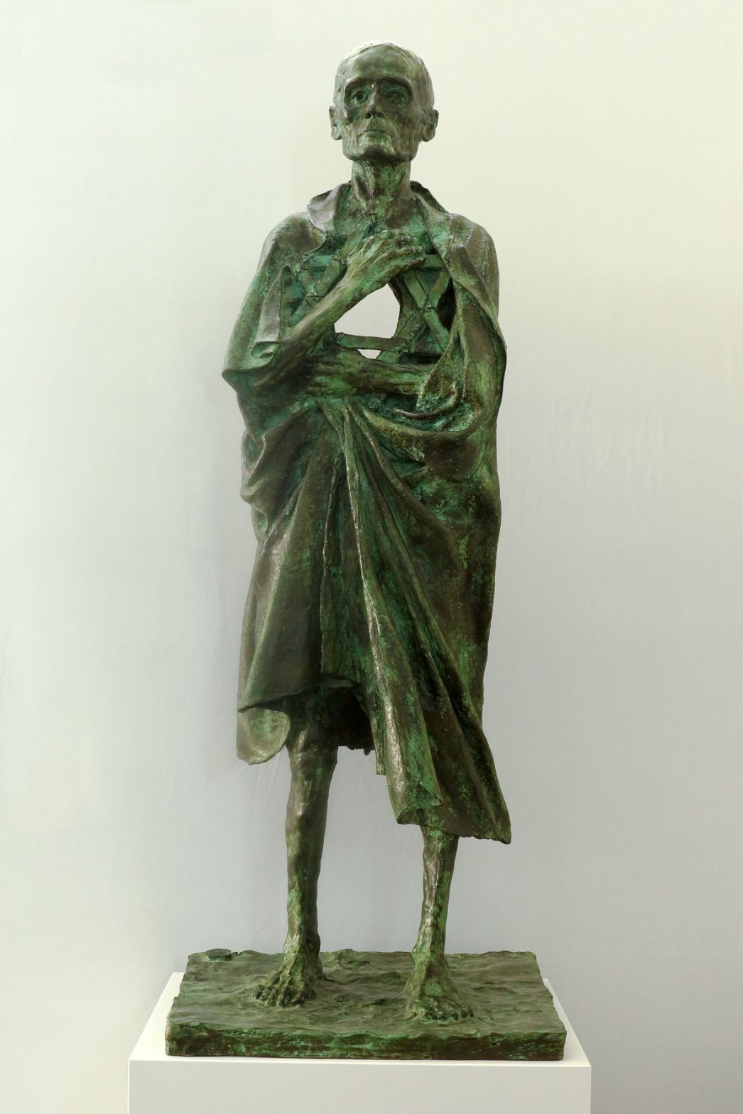 A bronze culture of an emaciated prisoner with a tattered blanket draped around him. His chest is hollow.