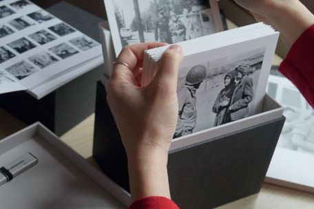 The picture shows hands of a person leafing through the educational material "Penig-Box".