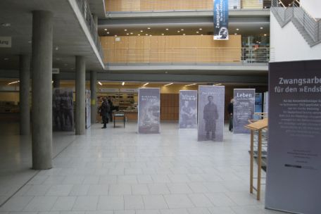 Ein großes Foyer mit zwei Galerien. Im Foyer verteilt stehen die Banner, aus denen die Wanderausstellung besteht.