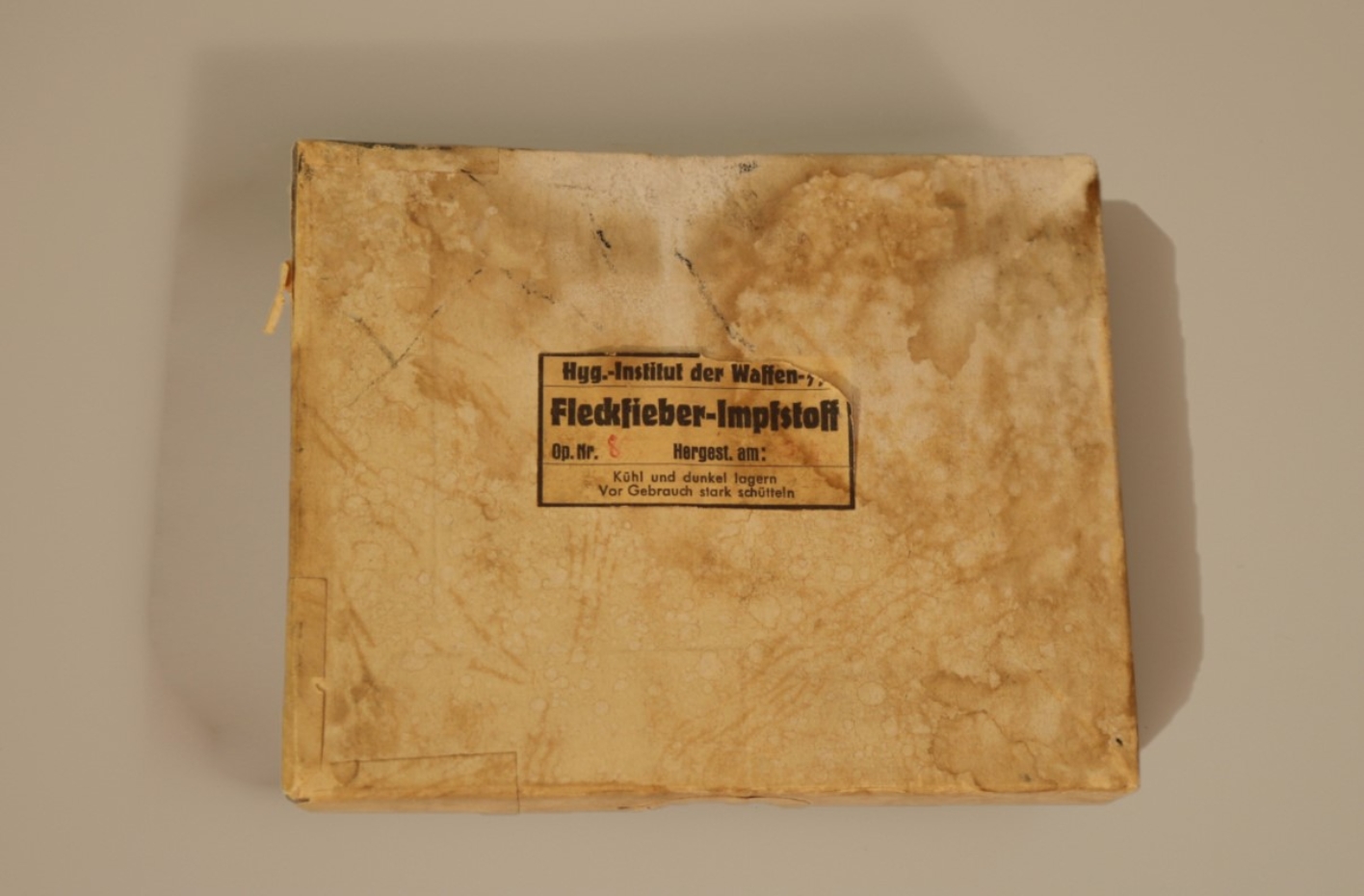 Ein vergilbtes Paket mit der Aufschrift "Hygienisches Institut der Waffen-SS - Fleckfieber Impfstoff"