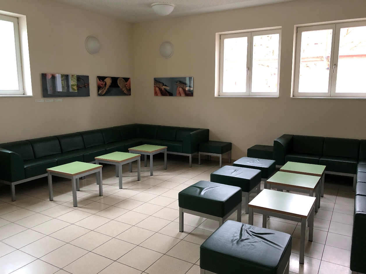 A corner of the room with many seats and small tables. Photos hang on the walls.