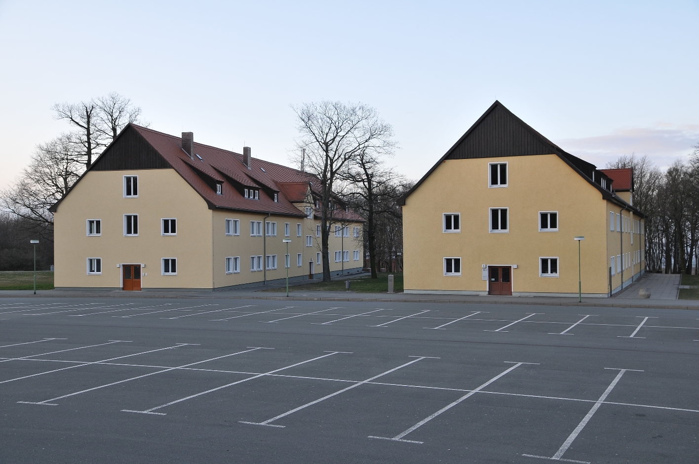 The International Youth Meeting Center of the Buchenwald Memorial. Two former SS barracks, now converted, with an empty parking lot in front of them.