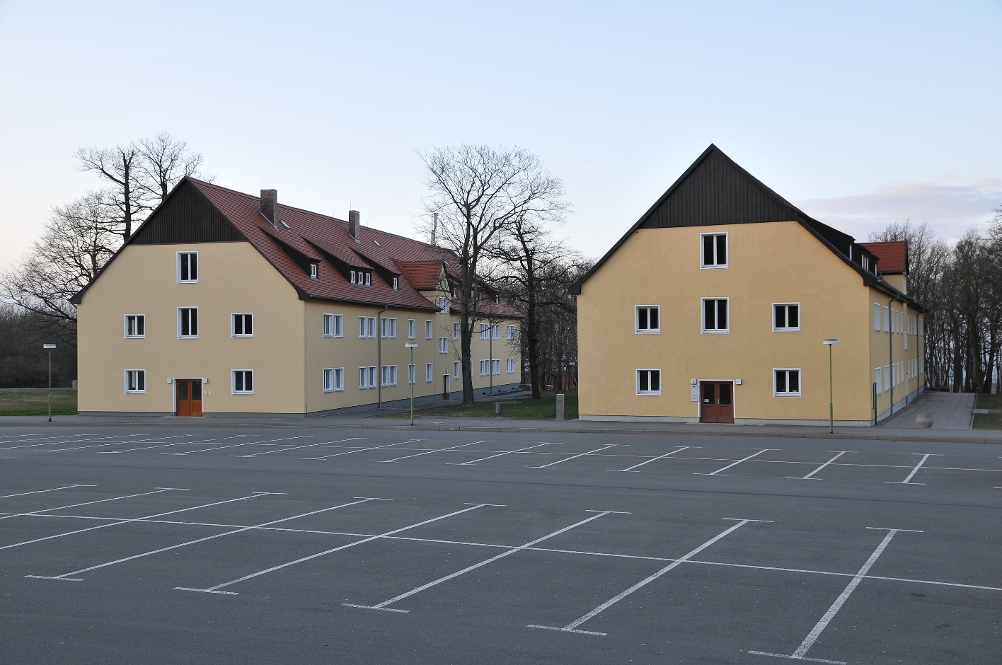 Die Internationale Bildungsstätte der Gedenkstätte Buchenwald. Zwei ehemalige, inzwischen umgebaute SS-Kasernen, davor ein leerer Parkplatz