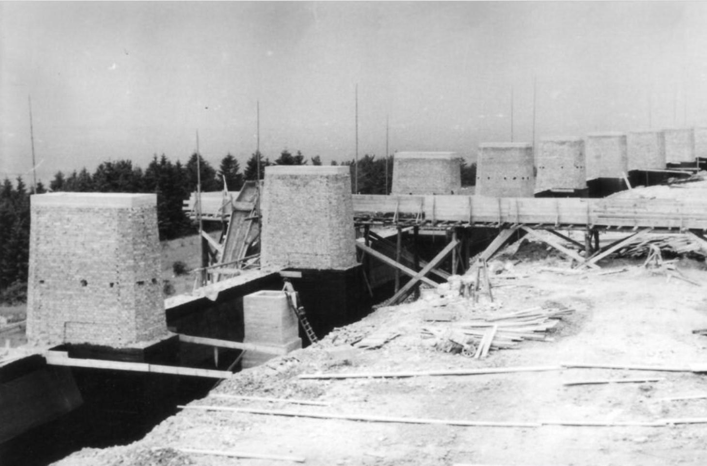 Bricked-on pedestals for the fire bowls on the Street of Nations during construction. In total, 7 pedestals are visible in the picture. The rest of the picture shows building material and wooden scaffolding.