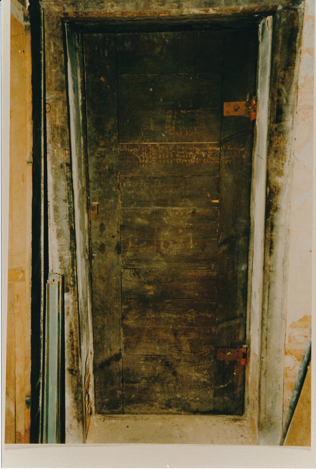 Frontal view of a locked cell door in Eisfeld Castle. The door is heavily rusted.