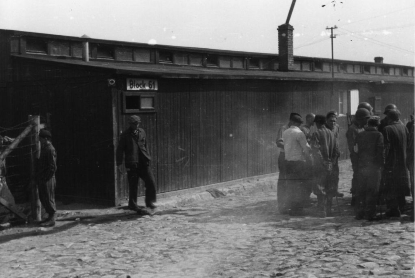  Befreite Häftlinge im Gespräch mit amerikanischen Soldaten einer Holzbaracke.