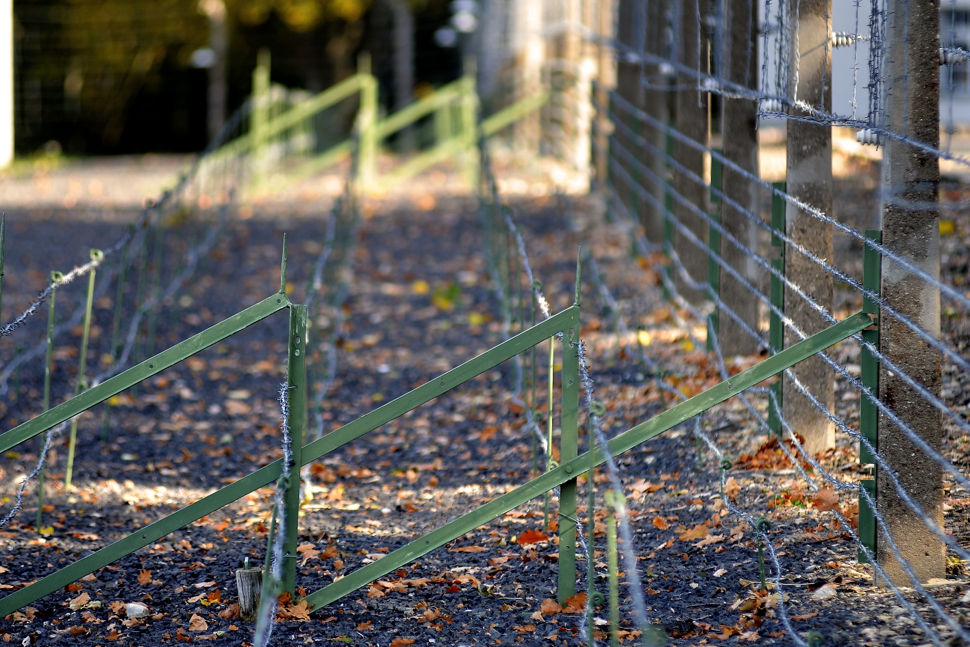 From the picture you can see several square metal frames with barbed wire set up in three rows as trip wires in front of the camp fence.