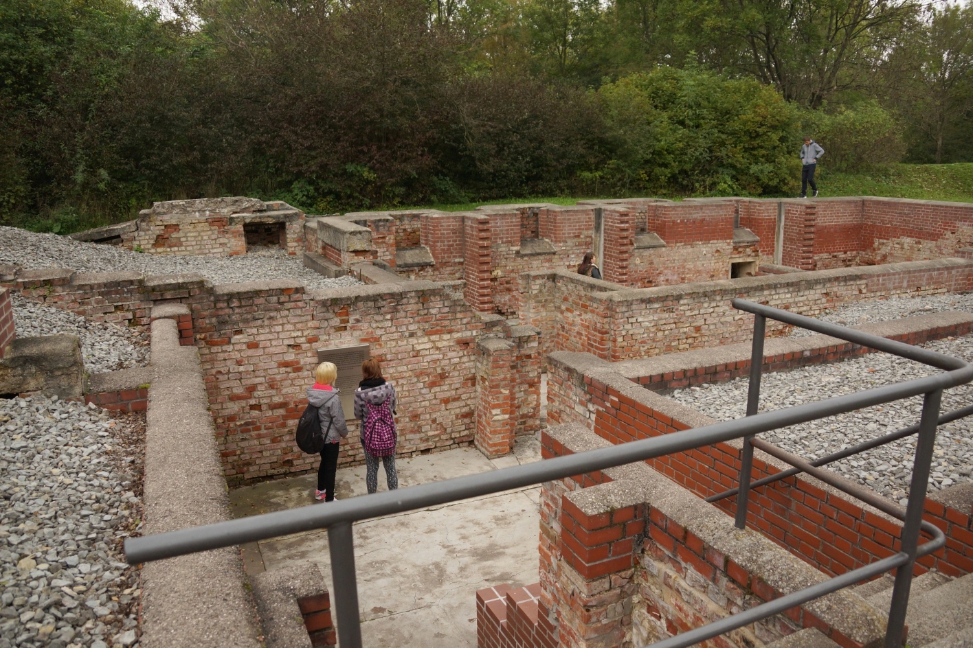 Zwei Gäste vor der Dietrich-Bonhoeffer Gedenktafel. Die verwinkelten Mauerreste zeigen noch den Grundriss des ehemaligen Kellers.