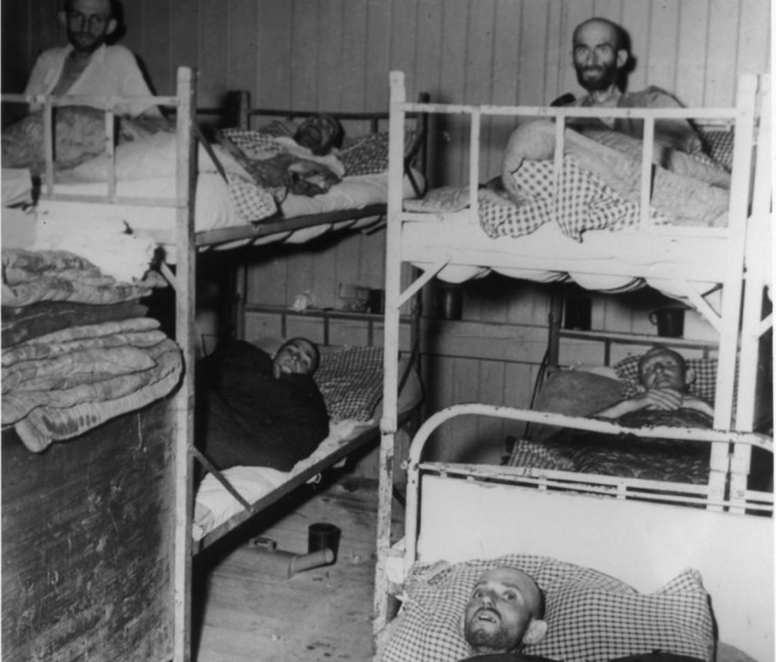 Blick in eine Baracke des Häftlingskrankenbaus nach der Befreiung. Rechts in der Mitte der ungarische Häftling Johann Csillag.