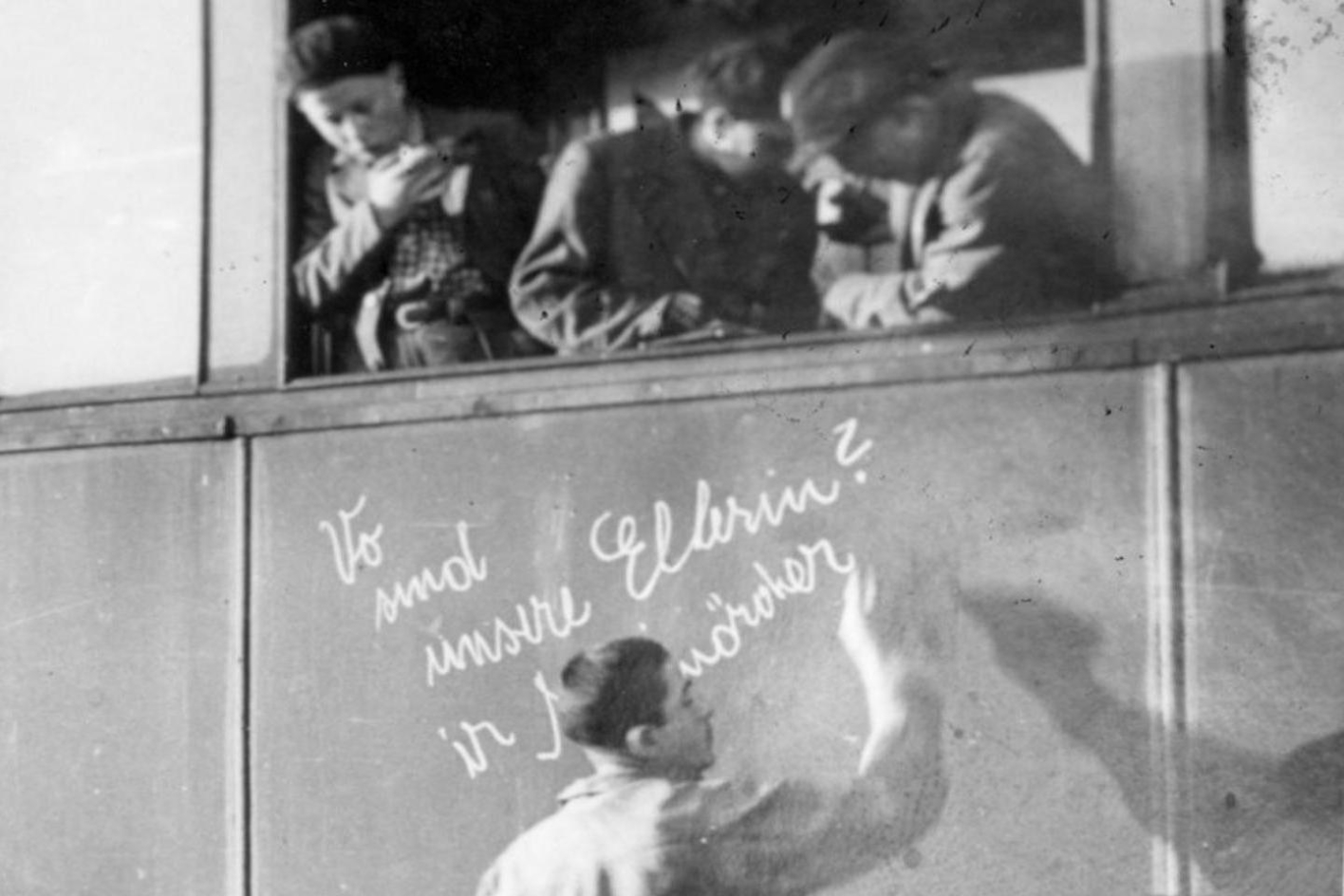 Liberated children and juvenile prisoners of Buchenwald concentration camp at Weimar Central Station in the carriage of a train to Ecoui. Josek Dziubak writes the inscription "Where are our parents? You murderers".
