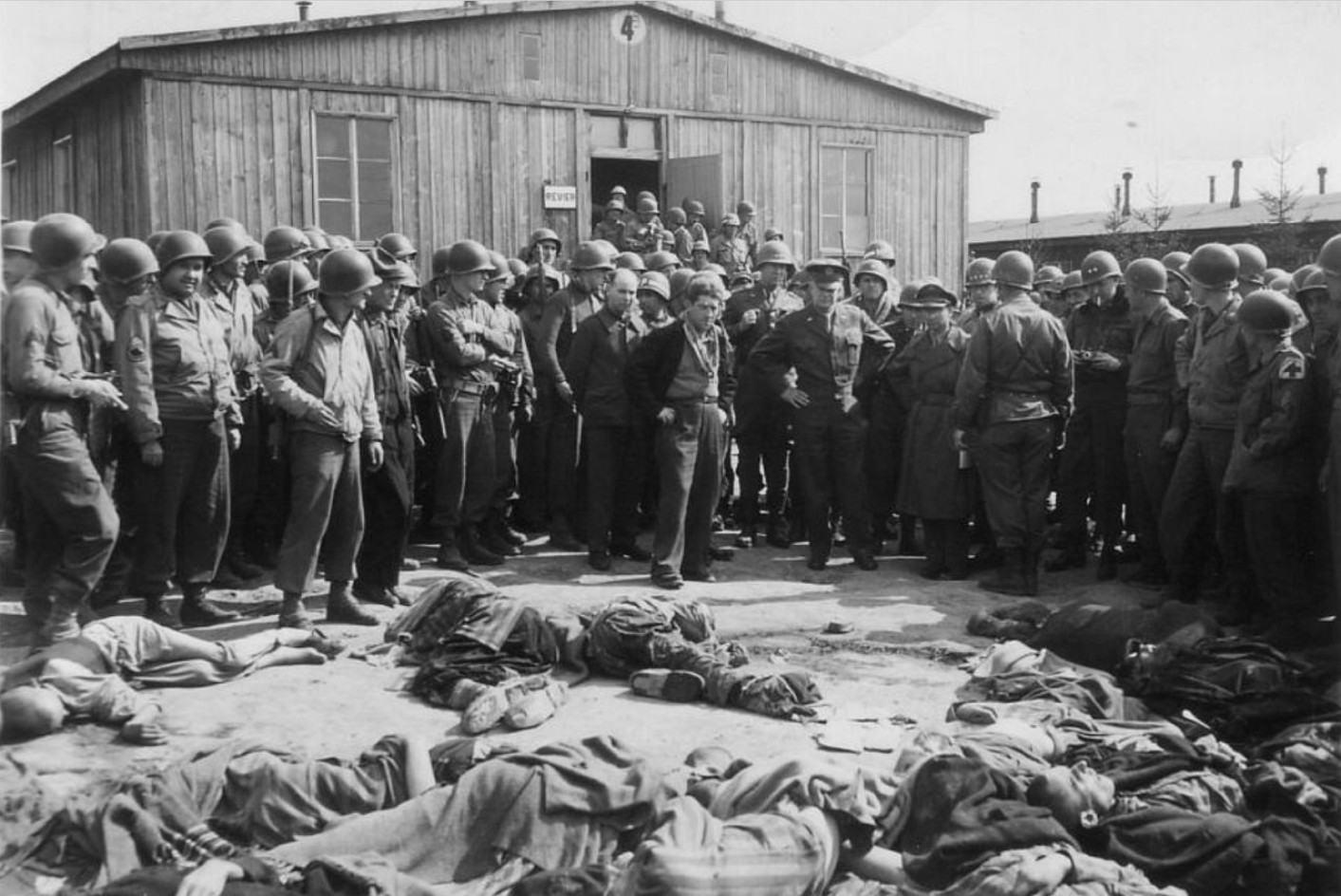 General Eisenhower besucht das befreite Außenlager Ohrdruf. Links von ihm: Einer der wenigen Überlebenden. Im Hintergrund ist Block 4, eine der Revierbaracken im Nordlager, zu sehen.