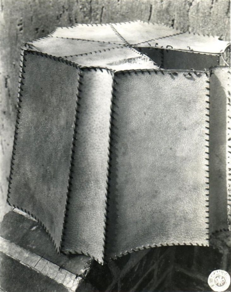 The picture shows a large lampshade sewn together from square pieces of skin on the sides and triangular pieces of skin on the top. 