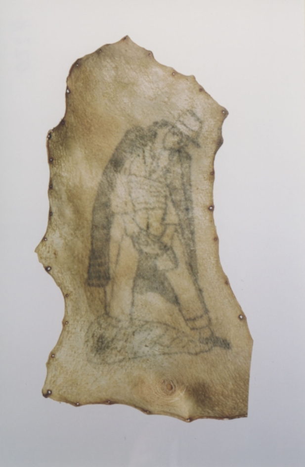 Human skin with tattoo showing a man with a cape. The skin was cut from the body with irregular edges and tanned.