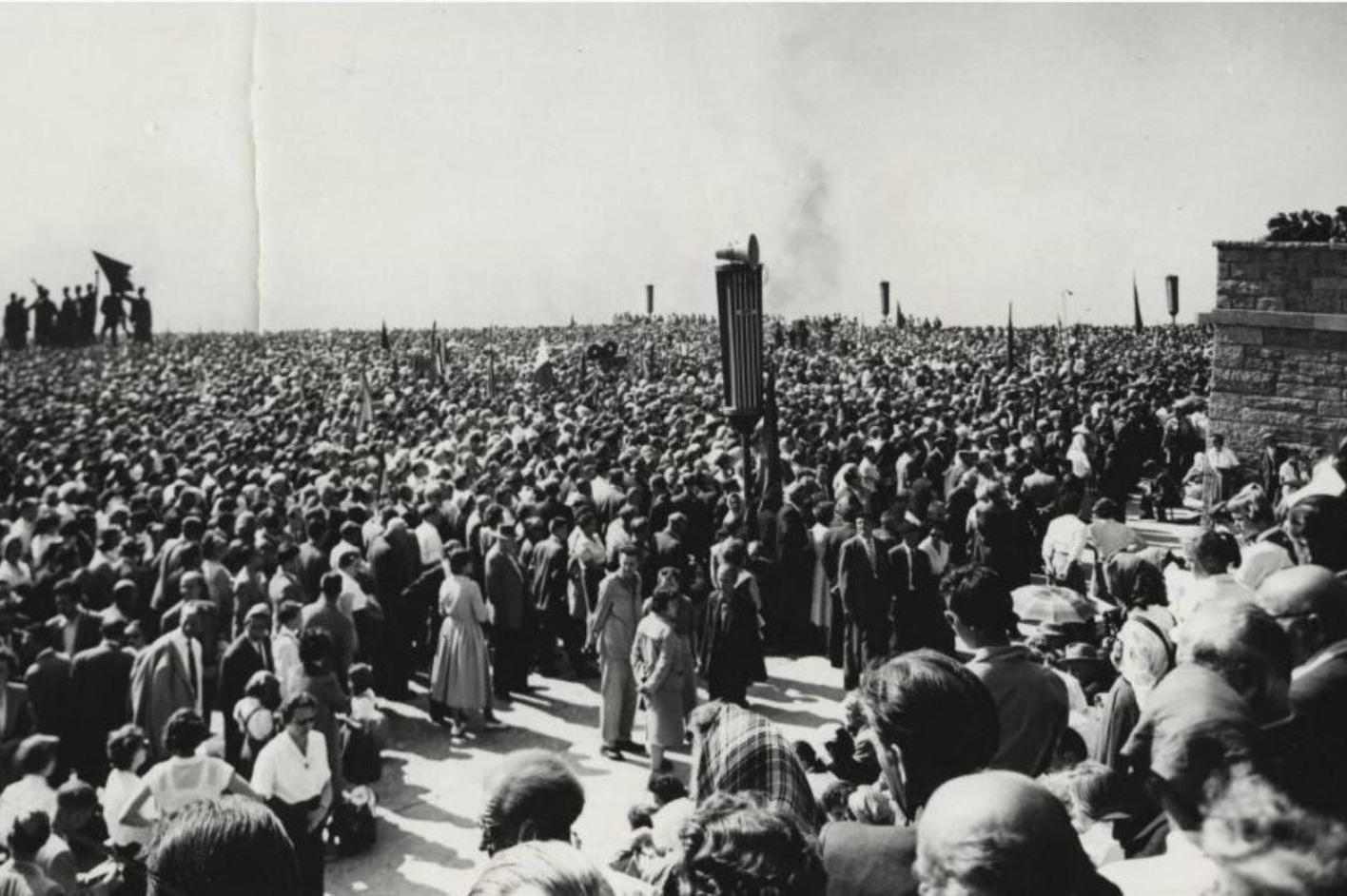 Eine große Menschenmenge hat sich zwischen Glockenturm und Fritz Cremers Figurengruppe versammelt. Das Bild zeigt Menschen, soweit das Auge reicht, nur die Bronzefiguren ragen heraus. Über das Gelände verteilt sind mehrere Lautsprecher.