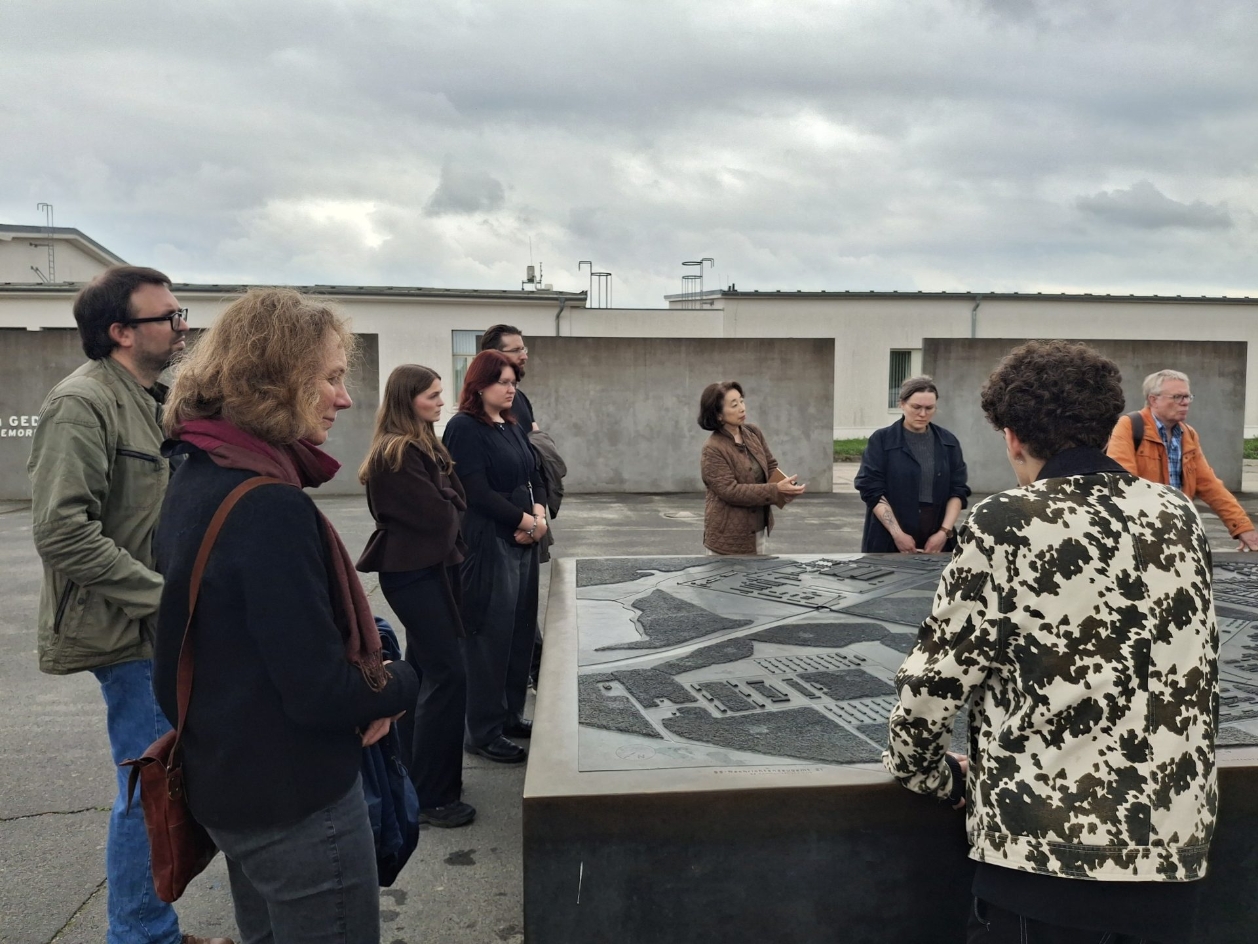 Mehrere Menschen stehen im Freien um ein Modell. Das Modell zeigt das Gelände des Konzentrations- und Speziallagers Sachsenhausen.