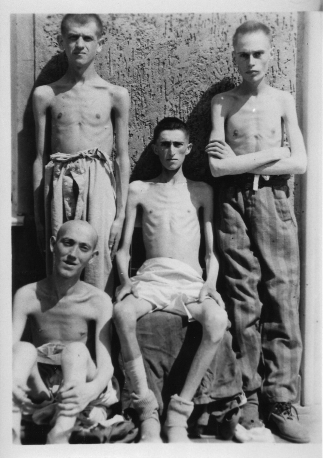  Four young prisoners with their upper bodies exposed in front of one of the stone blocks. Sitting in the center of the picture: the Hungarian Jewish prisoner Jakob Rosenthal .