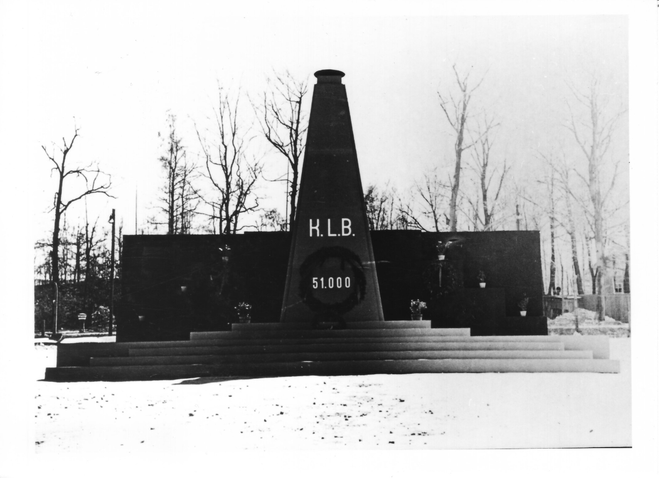 Ein hölzerner Obelisk auf einem hölzernen Podest. Er trägt die Aufschrifft "K.L.B - 51.000".