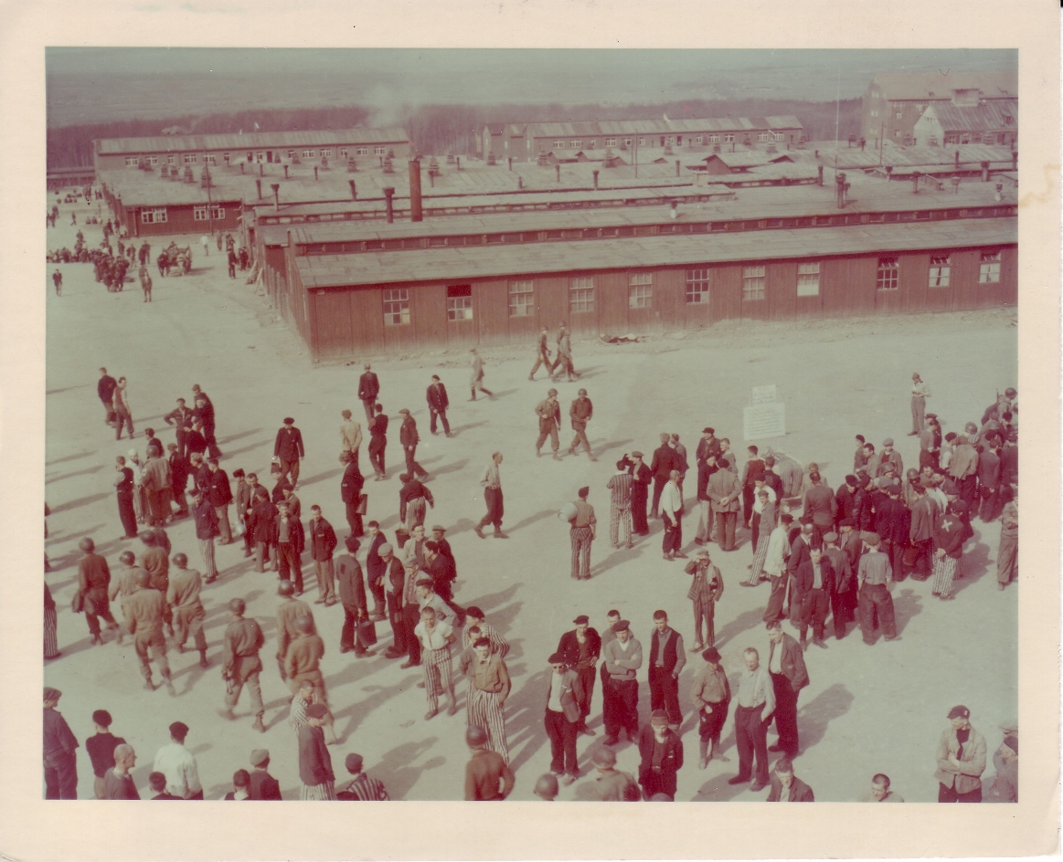 Blick vom Torgebäude über das Lager. Auf dem Appellplatz stehen befreite Häftlinge und US-Soldaten. Ganz rechts im Hintergrund das Kammergebäude.