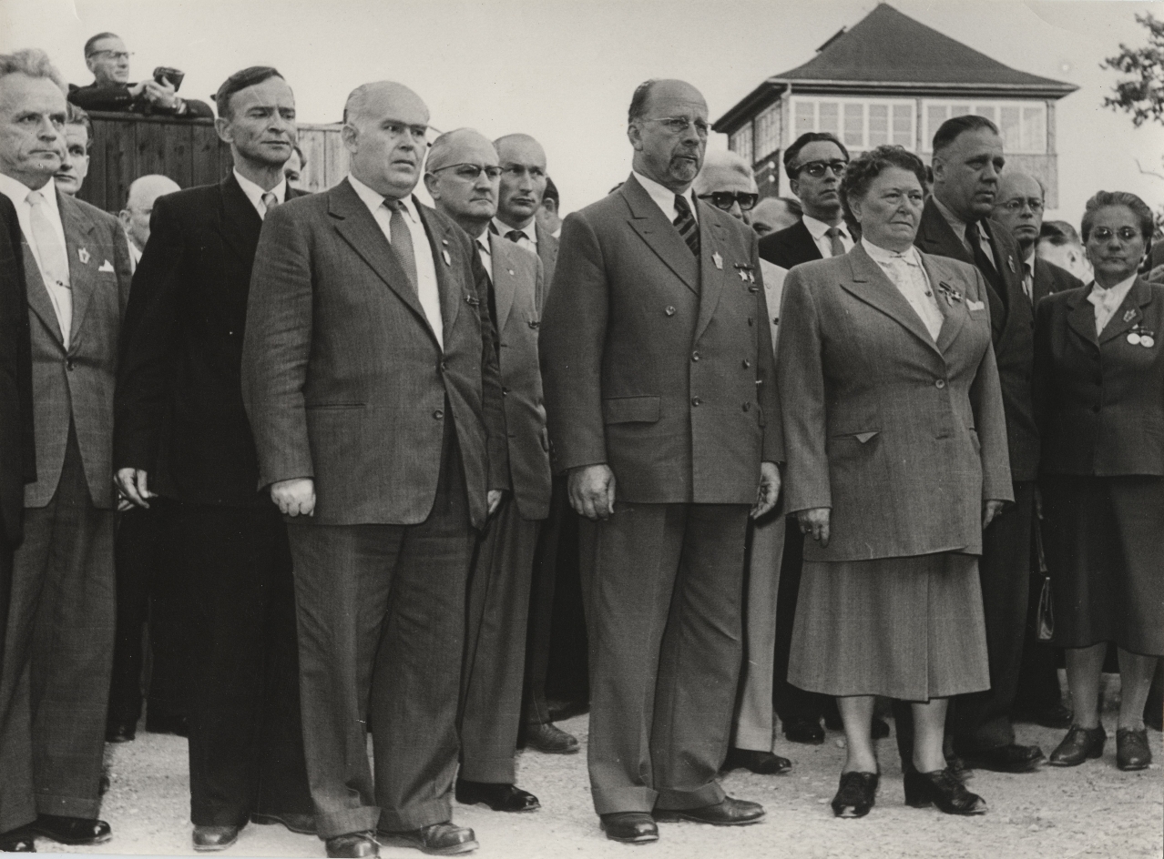 Participants in the inauguration ceremony of the Buchenwald National Memorial in the courtyard of the crematorium. In the background, one of the watchtowers.