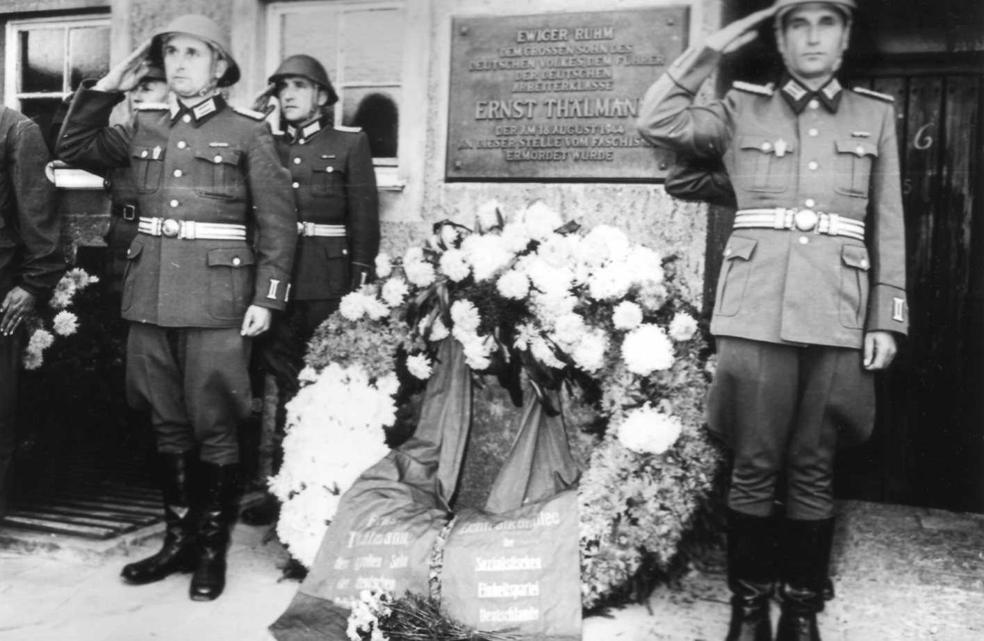 Drei Soldaten der NVA salutieren um einen Kranz der vor der Gedenktafel für Ernst Thälmann am Krematorium niedergelegt wurde.