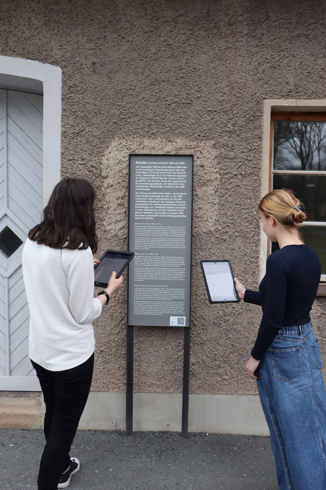 Teilnehmerinnen des Workshops erkunden den Außenbereich der sowjetischen Verwaltungsbaracke mit Ipads