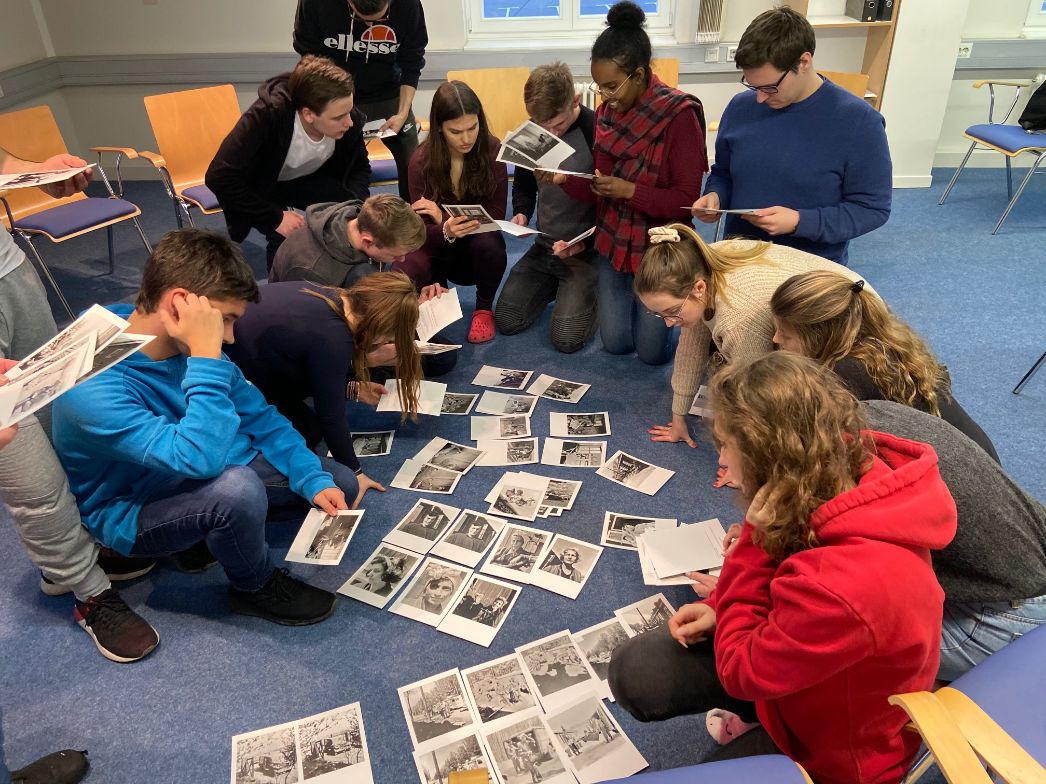 A group of students sitting on the floor and working with photos of the "Penig Box".