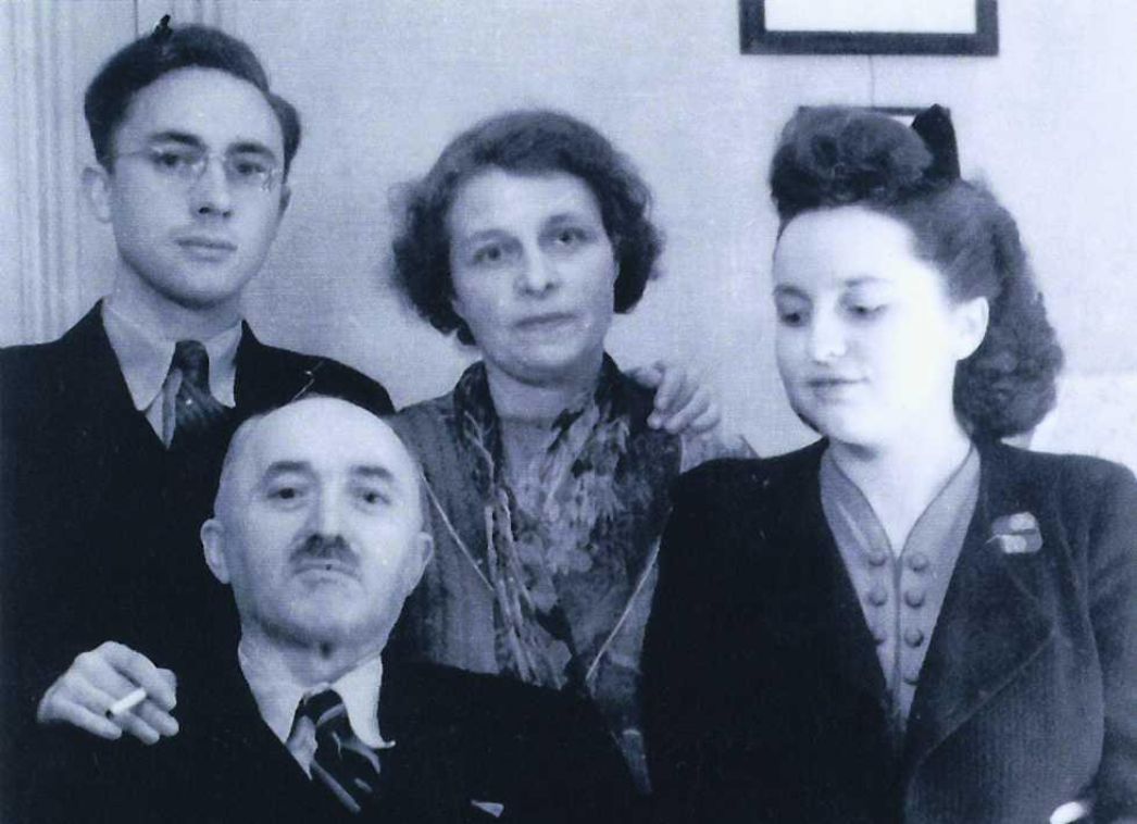 Group shot of Jacqueline Marié. To her right are her mother and brother, in front of them sits her father at a desk