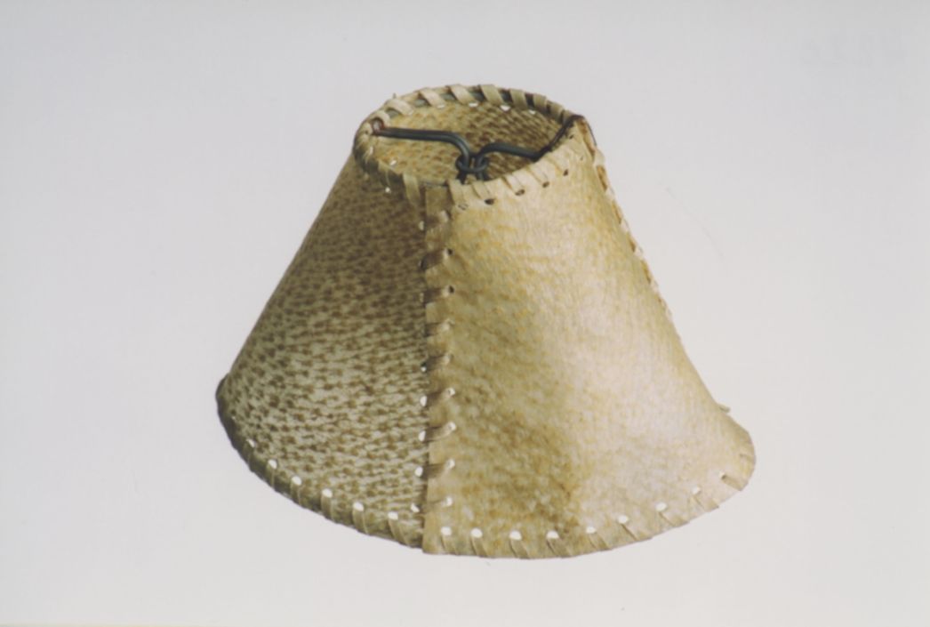 On display is a lampshade made from tanned human skin. The shade has a yellowish colour and consists of two pieces of skin joined together with coarse stitching.