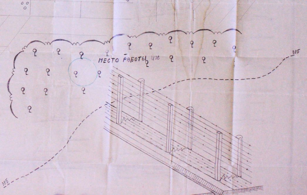 The drawing shows a section of the fence at the front left, which consists of two rows of barbed wire. Behind the fence, running roughly diagonally across the picture plane, is a multiple curved dashed line inscribed at both ends with the number 385. In the upper right, a wavy line indicates an area where small symbols suggest trees or forest. A Cyrillic lettering is written in it. At the upper edge of the image, straight lines suggest that the original shows further motifs outside the image section.