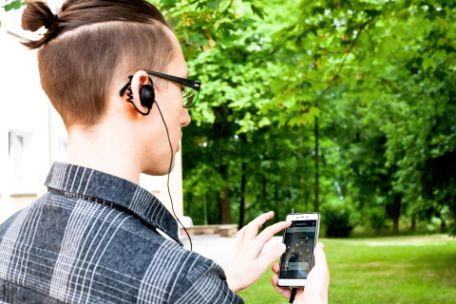 A visitor uses the I-Guide app while touring the memorial. The smartphone used is equipped with headphones.