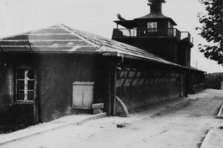 In front on the left is the detention cell building in the right wing of the gate building. In the center is the main watchtower above the camp gate. Behind it is the left wing of the gate building.