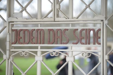 View of the white camp gate with the inscription "To each his own" in red letters, which can be read from the inside