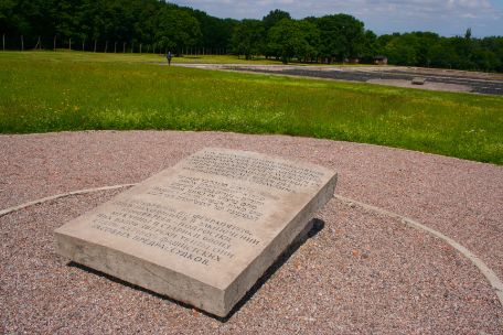 The massive memorial stone stands on the ground in a circle drawn around it. The location of the memorial stone is surrounded by a lawn.
