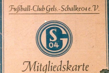 Zusehen ist eine Mitgliedskarte des FC Schalke 04 für Arthur Herz. Sie hat eine lachsfarbende Farbe und ist an den Rämdern eingerißen. Das Schalke 04 Logo ist gut sichtbar in der Mitte der Mitgliedskarte zu sehen.