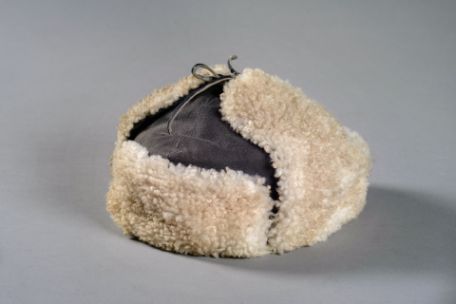 Eine helle Pelzmütze mit hochgeklappten Ohren.