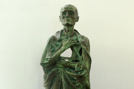 Zu sehen ist eine Bronzeskultur eines abgemagerten Häftlings, der sich eine zerschlissene Decke umgehängt hat.