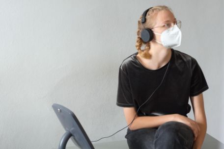 A young woman with headphones is sitting at a listening station. 