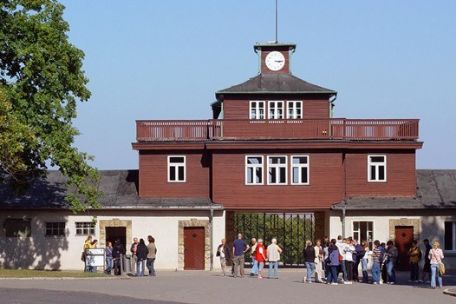 The gate building. Two wings, above a small tower with a clock at the top. Under the tower the gate. In front of it groups of visitors
