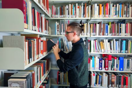 A user pulls a book from one of the book shelves in the memorial library.