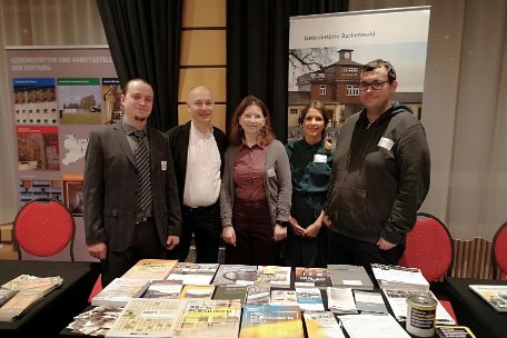 Das Team der Gedenkstätte Buchenwald steht gemeinsam hinter einem Tisch, auf dem Informationsmaterialien ausliegen.