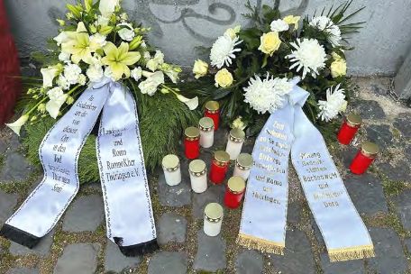 Zwei Kränze und Kerzen zum Gedenken an die ermordeten Sinti und Roma.
