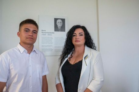 Julia Romantschenko und Ihr Sohn Kyryl vor der Namenstafel des Saals