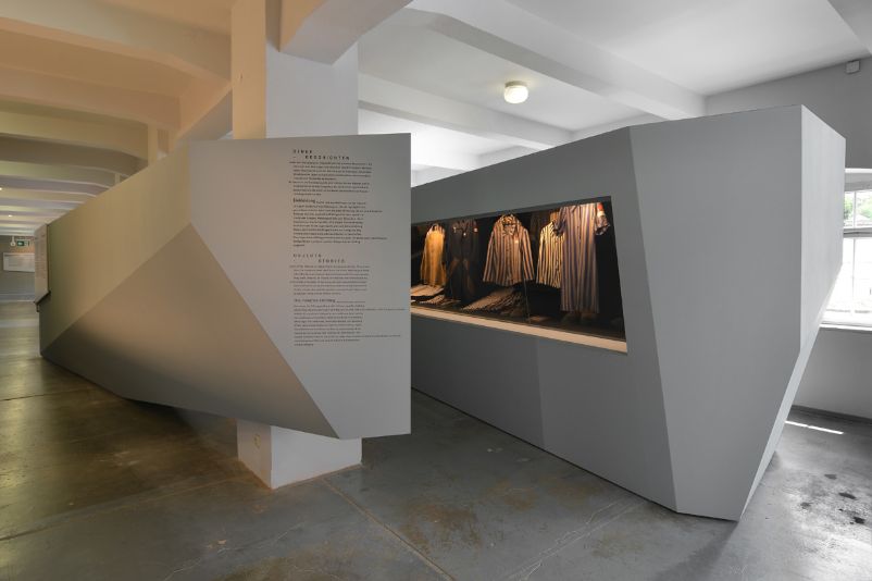 Exhibits in the concentration camp exhibition. The showcases are abstractly shaped and display items of clothing.