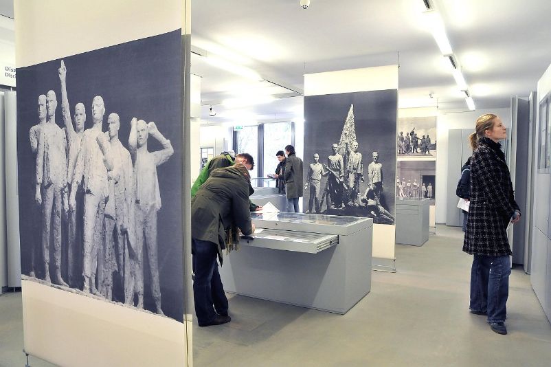 Das Foto zeigt Personen im Ausstellungsgebäude beim Lesen von Informationstafeln und Begutachten von Vitrinen.