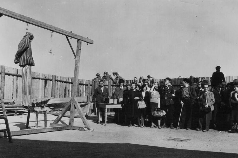 Einwohner Weimars bei der von den Amerikanern befohlenen Besichtigung des Konzentrationslagers Buchenwald. Sie stehen im Innenhof des Krematoriums vor dem Galgen, an dem eine Puppe in Häftlingskleidung hängt.