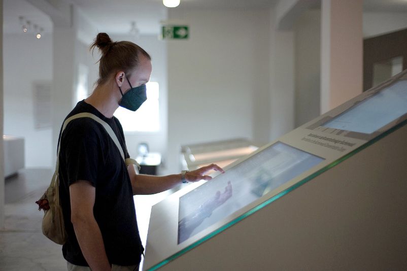 Ein junger Mann steht vor einem Touchscreen in der Ausstellung.