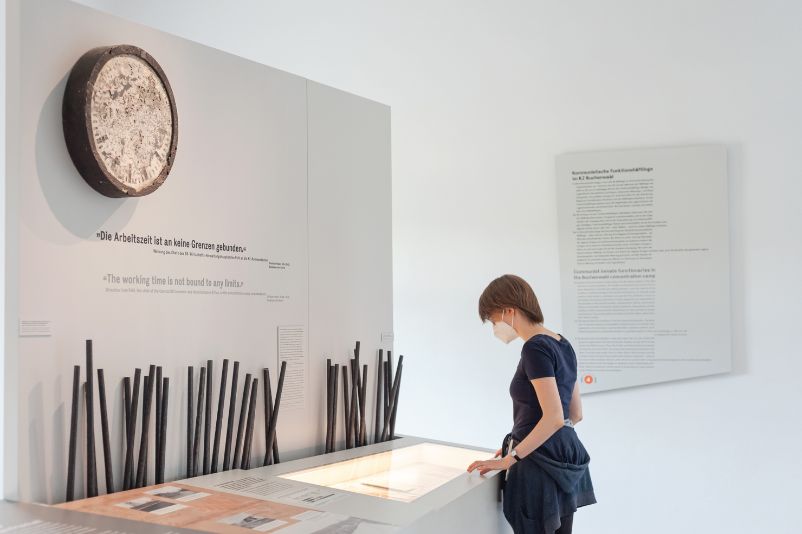A young visitor is standing by a clock in the exhibition area and is engrossed in the content laid out in front of it.